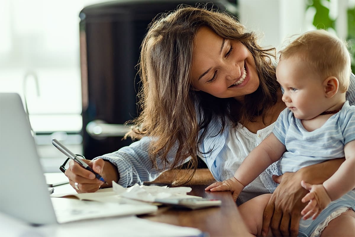 volksbank mittelhessen zukunftsplanerin sehr junge Mutter mit Baby sind entspannt im Homeffice und lachen